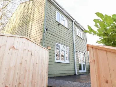 a green house with a wooden fence in front of it at Arnside House in Carnforth