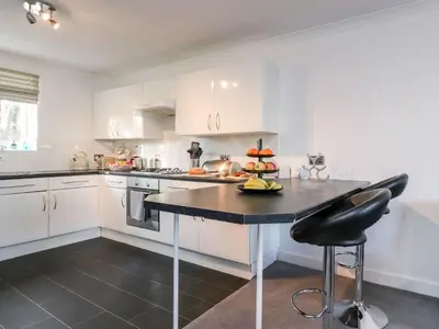 a kitchen with white cabinets and a black counter top at Arnside House in Carnforth