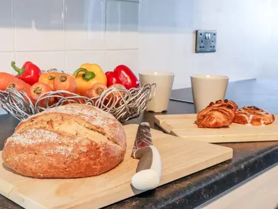 two cutting boards with a loaf of bread and a basket of vegetables at Arnside House in Carnforth