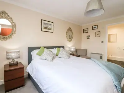 a bedroom with a large white bed and a mirror at Arnside House in Carnforth