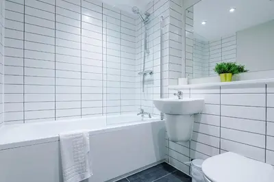 a white bathroom with a sink and a tub and a toilet at Stunning Top-Floor 2BR Free Parking & Stylish Stay in Liverpool