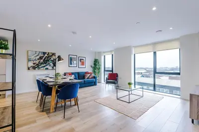 a living room with a table and a blue couch at Stunning Top-Floor 2BR Free Parking & Stylish Stay in Liverpool