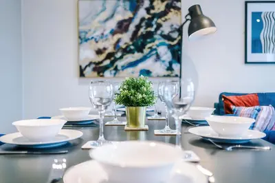 a table with plates and glasses and a plant on it at Stunning Top-Floor 2BR Free Parking & Stylish Stay in Liverpool