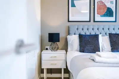 a bedroom with a bed and a night stand with a lamp at Stunning Top-Floor 2BR Free Parking & Stylish Stay in Liverpool