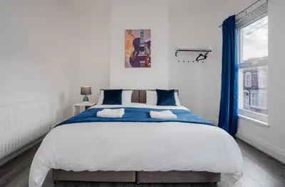 a bedroom with a large bed with blue curtains at Property is sold in Liverpool