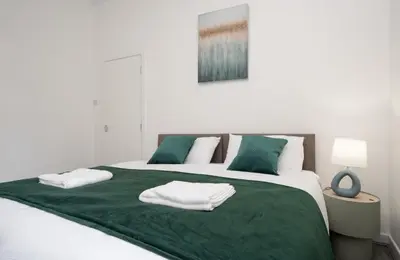 a bedroom with a large bed with green sheets and pillows at Property is sold in Liverpool