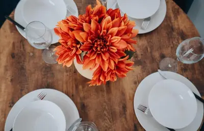 a table with white plates and a orange flower on it at Property is sold in Liverpool