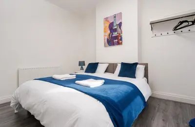 a bedroom with a large bed with blue and white sheets at Property is sold in Liverpool