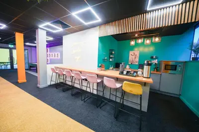 a kitchen with a bar with pink chairs in a room at URBAN HUB Student Accommodation in Preston