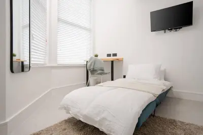 a bedroom with a bed with a tv on the wall at Private Stay by Anfield Shared Kitchen Parking in Liverpool