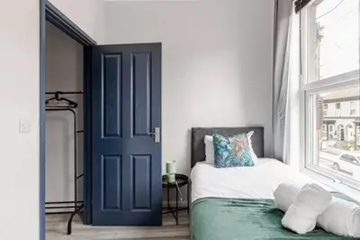a bedroom with a blue door and a bed and a window at 3Bed 2Bath house - Free Parking - Close to Everton & Liverpool FC- Managed by Chique Properties Ltd in Liverpool