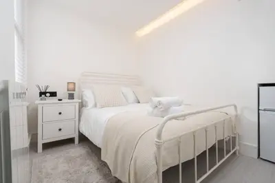 a white bedroom with a white bed and a night stand at Work Desk Shared Kitchen Budget Parking in Liverpool
