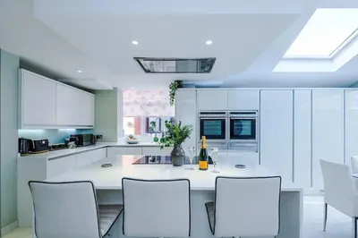 a kitchen with white cabinets and a table and chairs at 4 Bed House Relocators Trades and long stays in Samlesbury