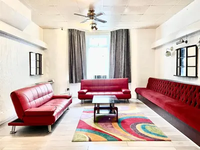 a living room with two red couches and a rug at The Stone House Hotel in Blackpool