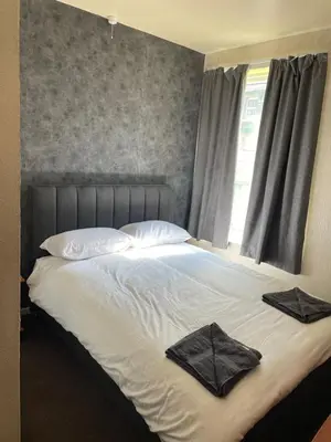 a bed with white sheets and pillows and a window at The Stone House Hotel in Blackpool