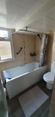 a bathroom with a white tub and a toilet at Ivy's in Grange Over Sands
