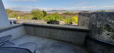 a balcony with two chairs and a stone wall at Ivy's in Grange Over Sands