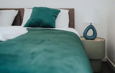 a bed with a green blanket and two pillows at Property is sold in Liverpool