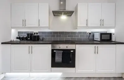 a white kitchen with white cabinets and a microwave at Property is sold in Liverpool