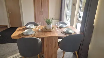 a dining room table with chairs and a wooden table with plates and glasses at Coastal Retreat Lodge in Morecambe