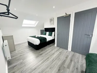 a bedroom with a bed and wooden floors and a door at Spacious Home, Central Liverpool, Sleeps 9, 2 Bathroom, Free Parking in Liverpool