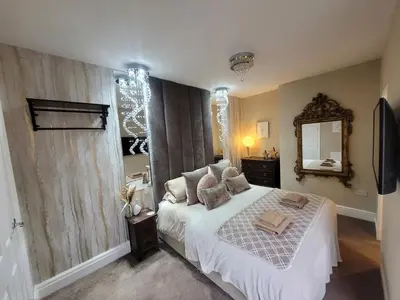 a bedroom with a white bed and a mirror at Tower Suites - HOT TUB sleeps 14 in Blackpool
