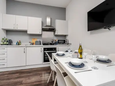 a kitchen with white cabinets and a table with wine glasses at Flat 1, Colquitt St, 1 Bed, L1 - Pass the Keys in Liverpool