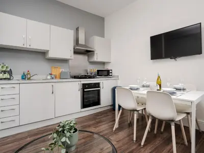 a kitchen with white cabinets and a table and chairs at Flat 1, Colquitt St, 1 Bed, L1 - Pass the Keys in Liverpool