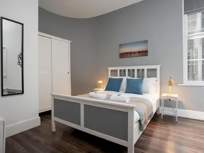 a white bedroom with a bed with blue pillows at Flat 1, Colquitt St, 1 Bed, L1 - Pass the Keys in Liverpool