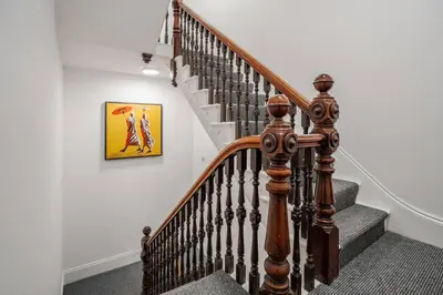 a staircase with a wooden rail and a painting on the wall at Private Kitchen & WM Work Desk Free Parking in Liverpool