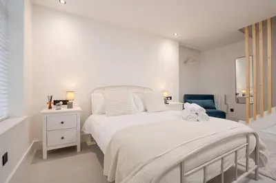 a white bedroom with a bed and a blue chair at Cosy Nook Kitchen w Washer & SofaBed Parking in Liverpool