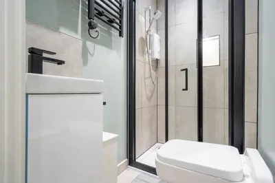 a bathroom with a white toilet and a shower at Cosy Nook Kitchen w Washer & SofaBed Parking in Liverpool