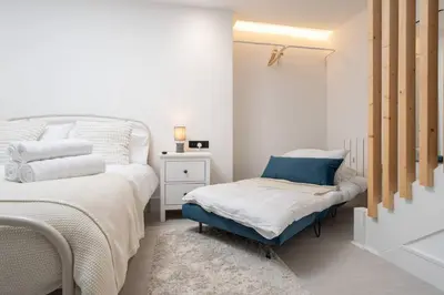 a white bedroom with a bed and a blue foot stool at Cosy Nook Kitchen w Washer & SofaBed Parking in Liverpool