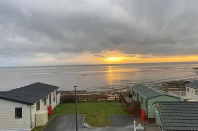 a view of the ocean with houses and the sunset at Seaside Retreat-Sleeps 8-Free Parking in Morecambe