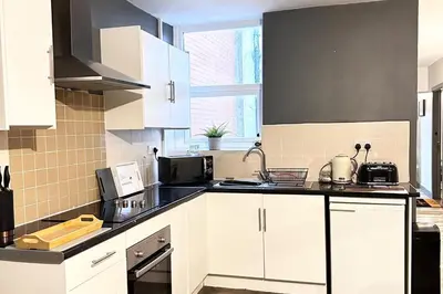 a kitchen with white cabinets and black counter tops at Oak Suite - 2 Bed - Sleeps 4 - Central Blackpool in Blackpool