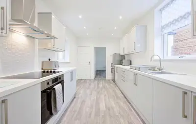 a white kitchen with white counters and white cabinets at 3 Bed House, Free Parking, Garden in Ince-in-Makerfield