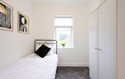 a white bedroom with a bed and a window at 3 Bed House, Free Parking, Garden in Ince-in-Makerfield