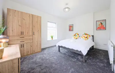 a bedroom with a bed and a large wooden cabinet at 3 Bed House, Free Parking, Garden in Ince-in-Makerfield