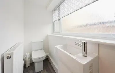 a white bathroom with a toilet and a sink at 3 Bed House, Free Parking, Garden in Ince-in-Makerfield