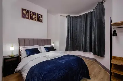 a bedroom with a bed with blue sheets and a window at 2 Bedroom, 1 Bathroom apartment in Blackpool