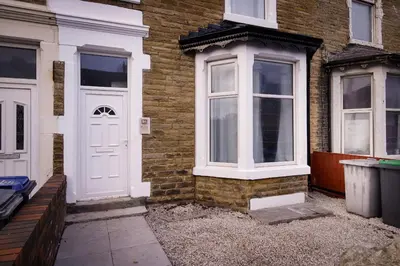 a white door on the side of a brick house at 2 Bedroom, 1 Bathroom apartment in Blackpool