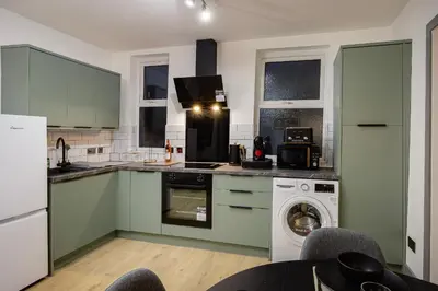 a kitchen with green cabinets and a washing machine at 2 Bedroom, 1 Bathroom apartment in Blackpool