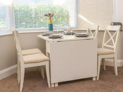 a white table with two chairs and a table with glasses on it at Lytham House in Lytham St Annes
