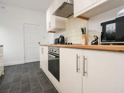 a kitchen with white cabinets and a microwave at Lytham House in Lytham St Annes