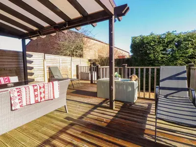 a deck with a pergola and a dog on it at Lytham House in Lytham St Annes