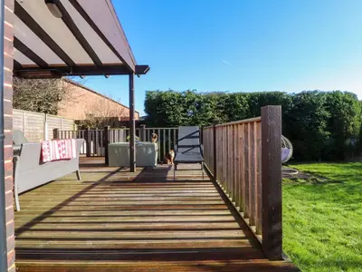 a wooden walkway with a bench and a fence at Lytham House in Lytham St Annes