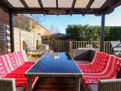 a patio with a table and chairs with red blankets at Lytham House in Lytham St Annes