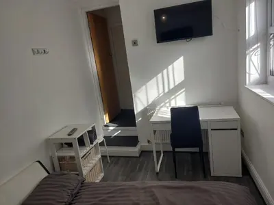 a room with a bed and a desk and a television at Anfieldstadiumroomz in Liverpool