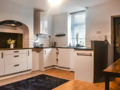 a kitchen with white cabinets and a large window at Nelson House in Clitheroe