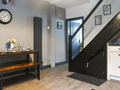 a living room with a staircase and a table and a clock at Nelson House in Clitheroe